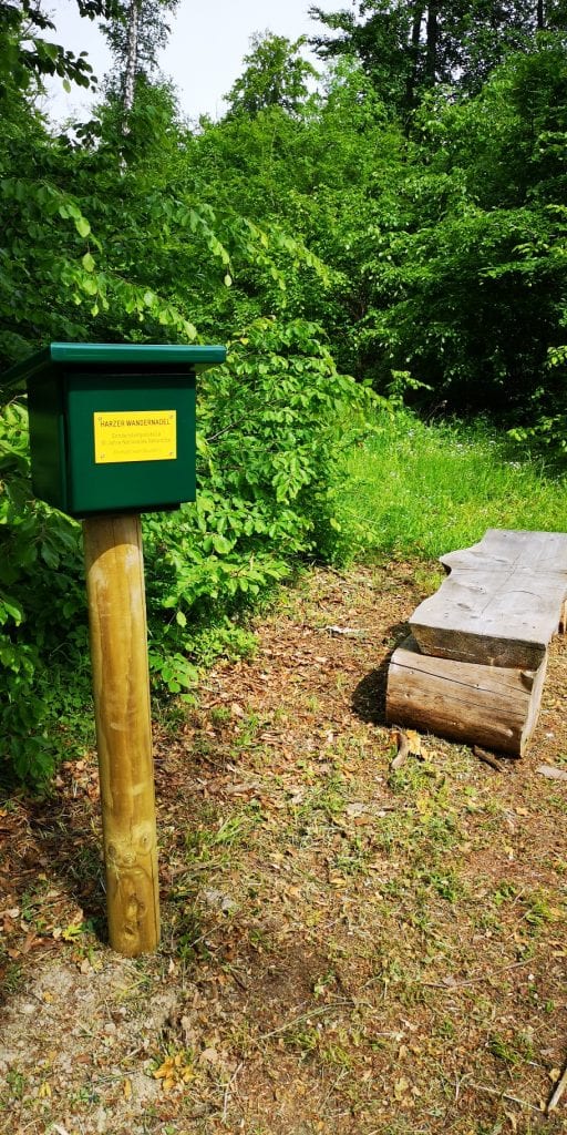 Wanderstempelstelle mit Holzbank im grünen Wald