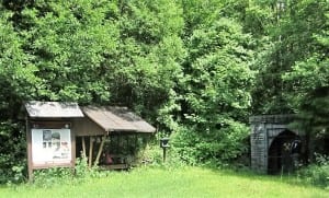 Forest hut with information board and stone portal in the countryside