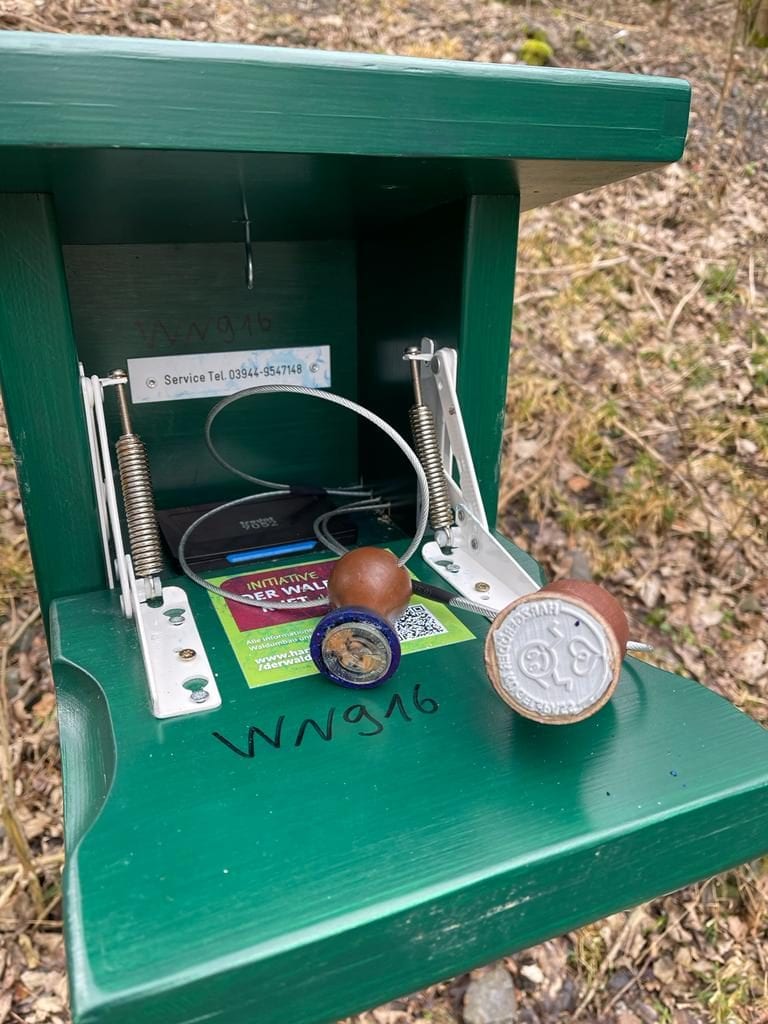 Grüne Stempelstation im Wald mit zwei Stempeln