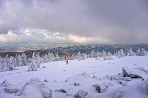 Verschneiter Brocken mit Wanderer. Winterlandschaft mit Blick ins Tal.