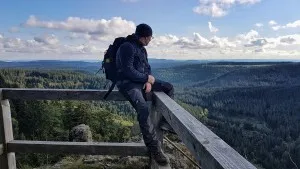 Wanderer genießt Aussicht über bewaldete Berge