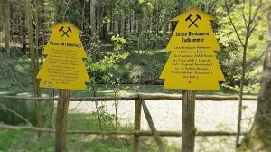 Yellow signs in the forest provide information about the water wheel and wheel chamber