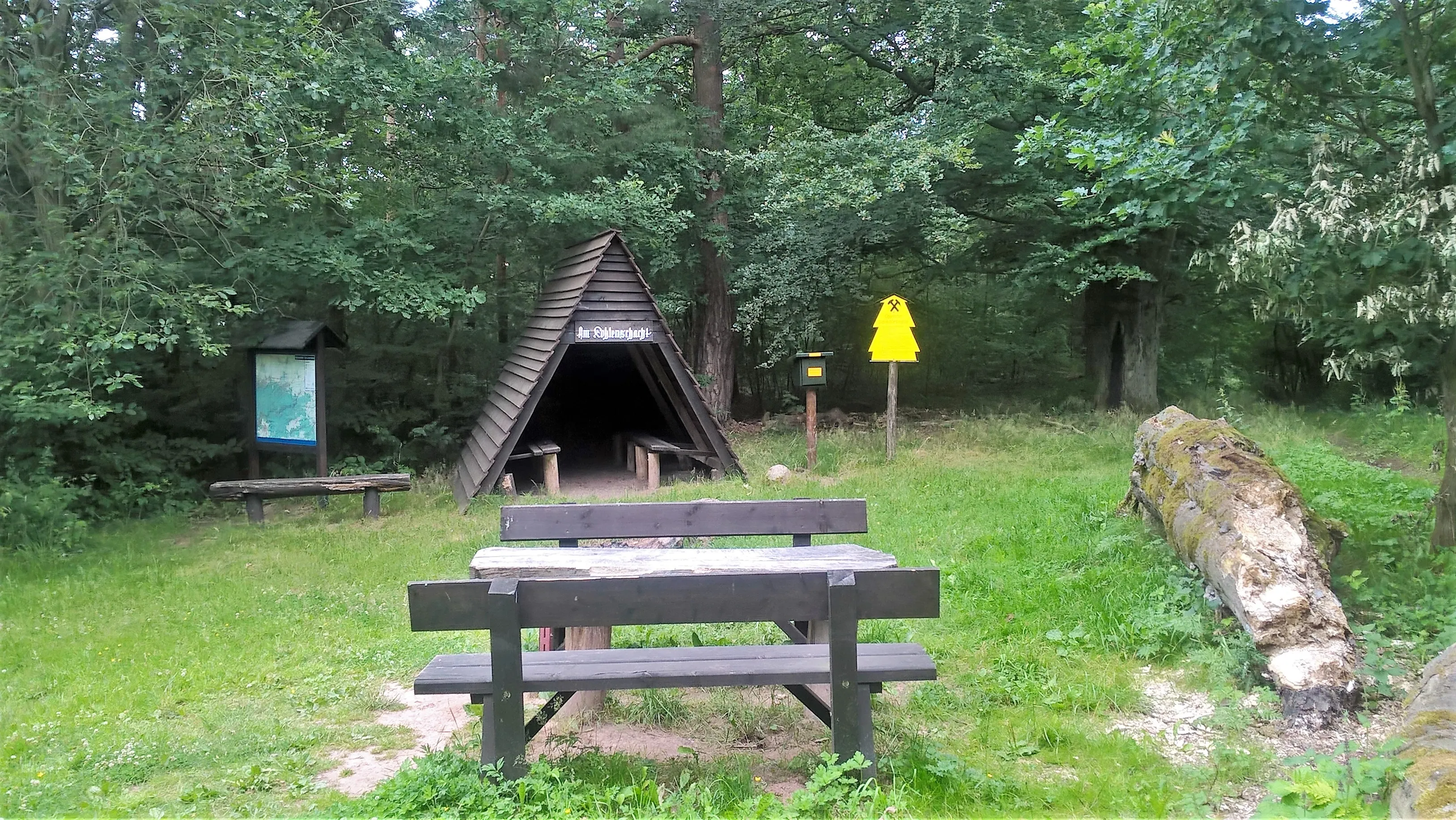 Waldhütte mit Sitzplatz und Infotafel im Grünen