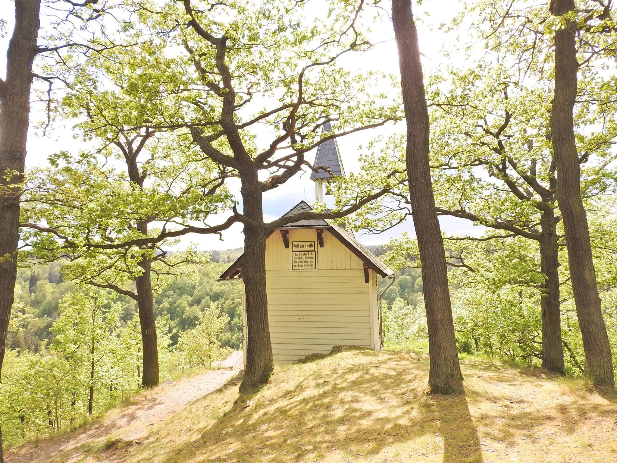 Kleine Kapelle im Wald auf sonnigem Hügel