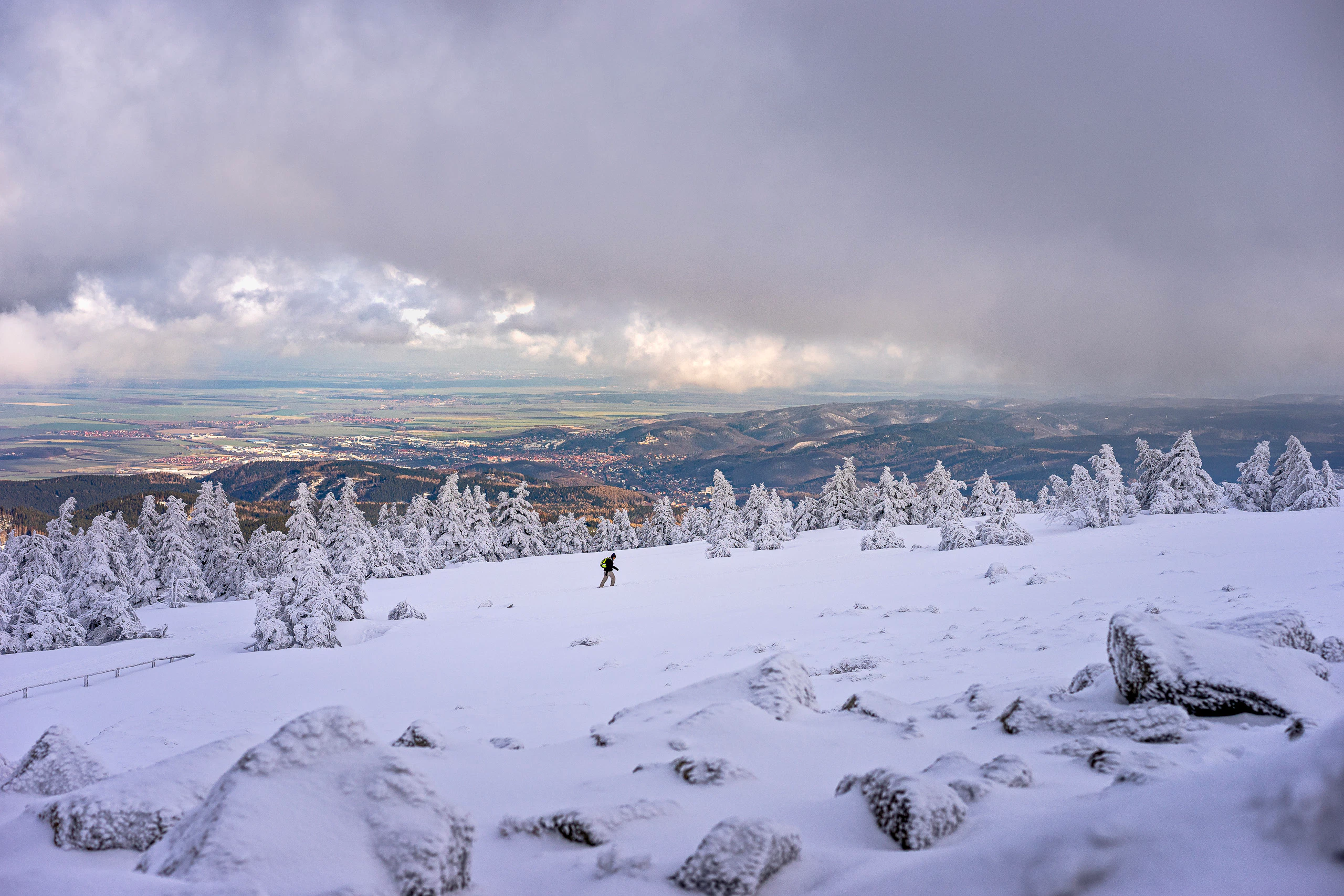 Verschneiter Brocken mit Wanderer. Winterlandschaft mit Blick ins Tal.