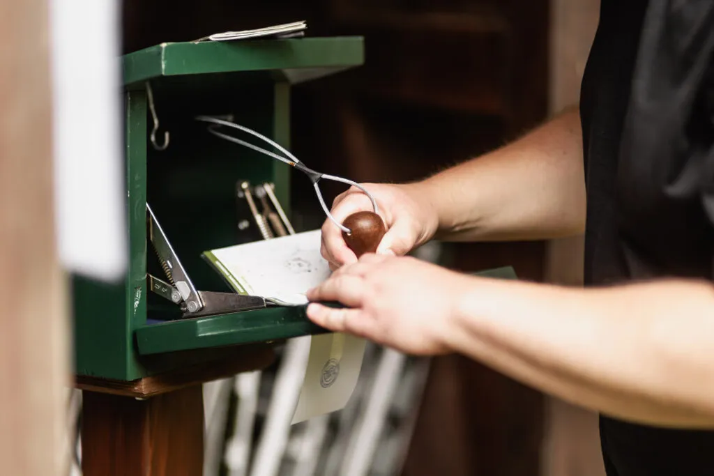 Person stempelt Papier an grünem Stempelkasten