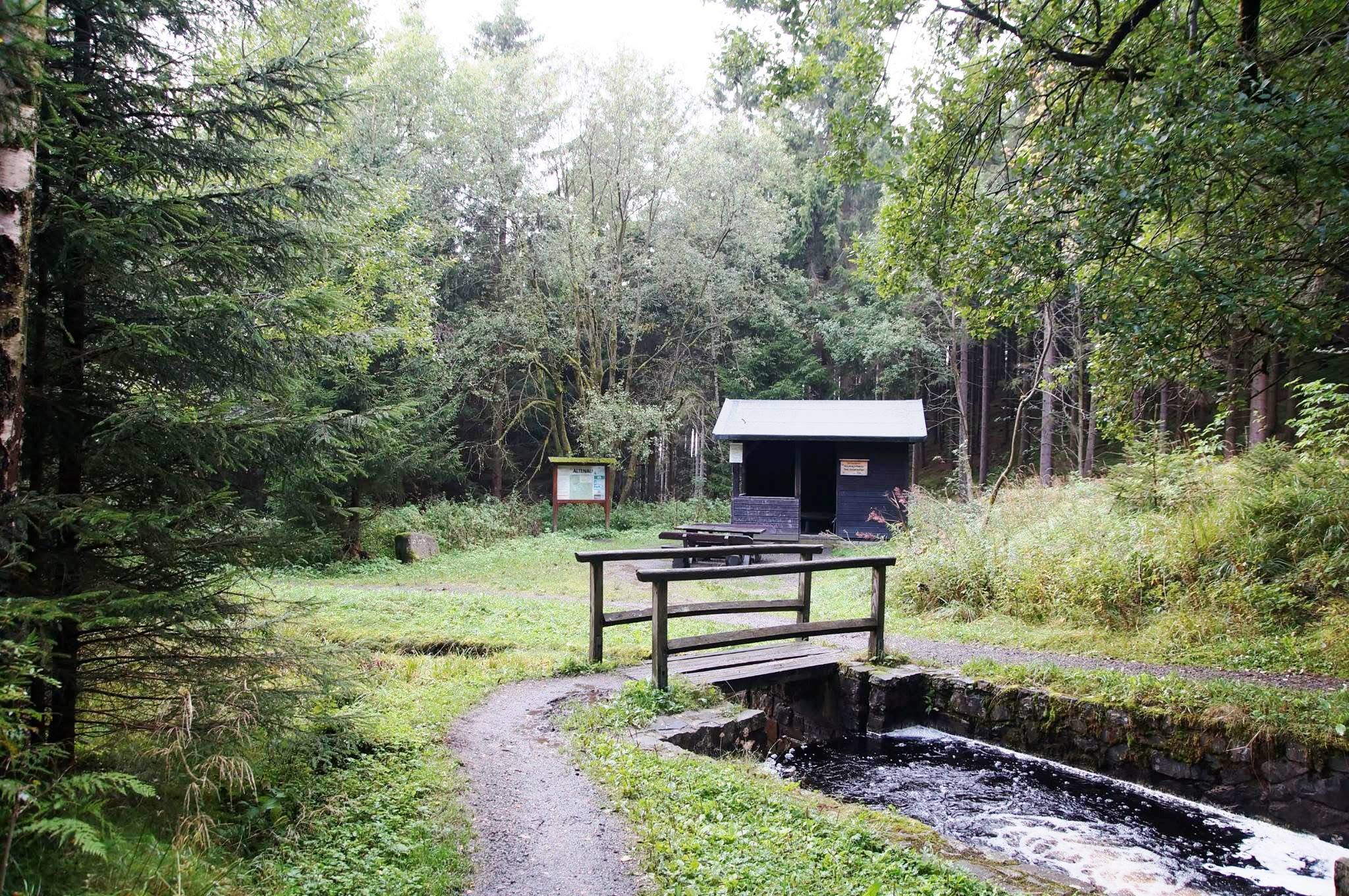 Skovhytte med vandløb og træbro på landet