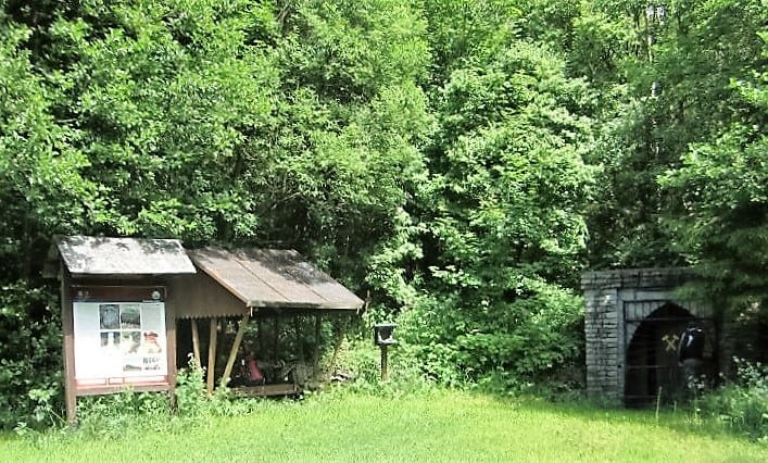 Waldhütte mit Infotafel und Steinportal im Grünen
