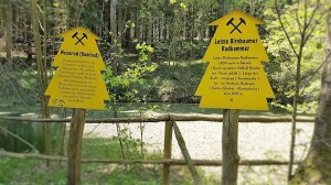 Gelbe Schilder im Wald informieren über Wasserrad und Radkammer
