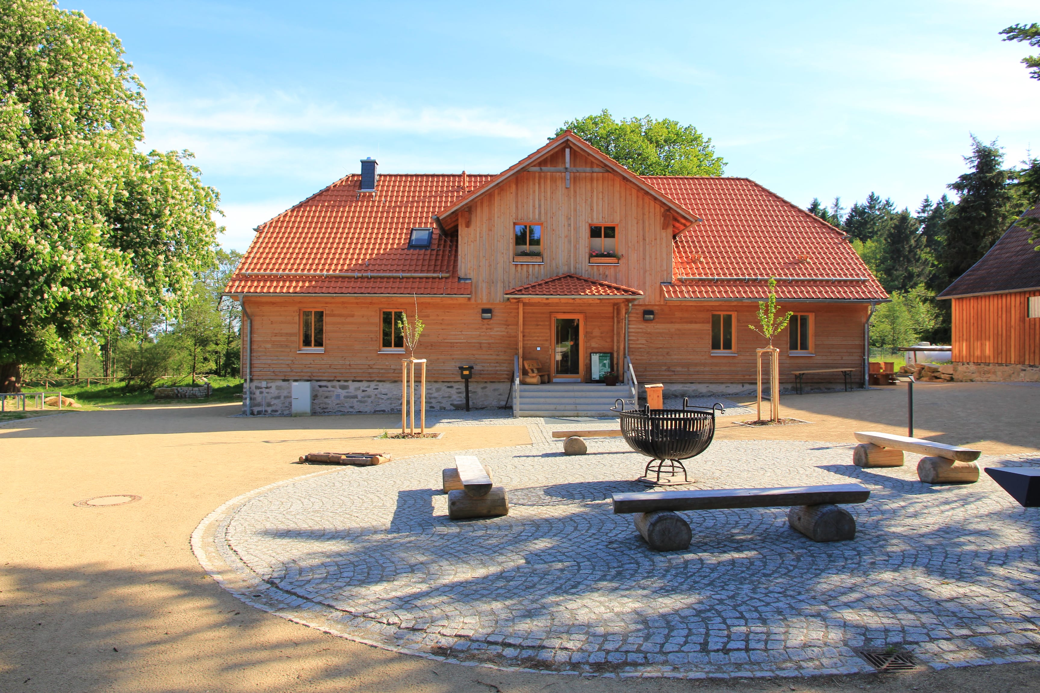 Maison en bois avec toit rouge et cour
