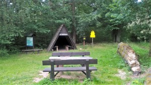 Waldhütte mit Sitzplatz und Infotafel im Grünen