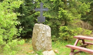 Schwarzes Kreuzdenkmal im Wald auf Steinblock