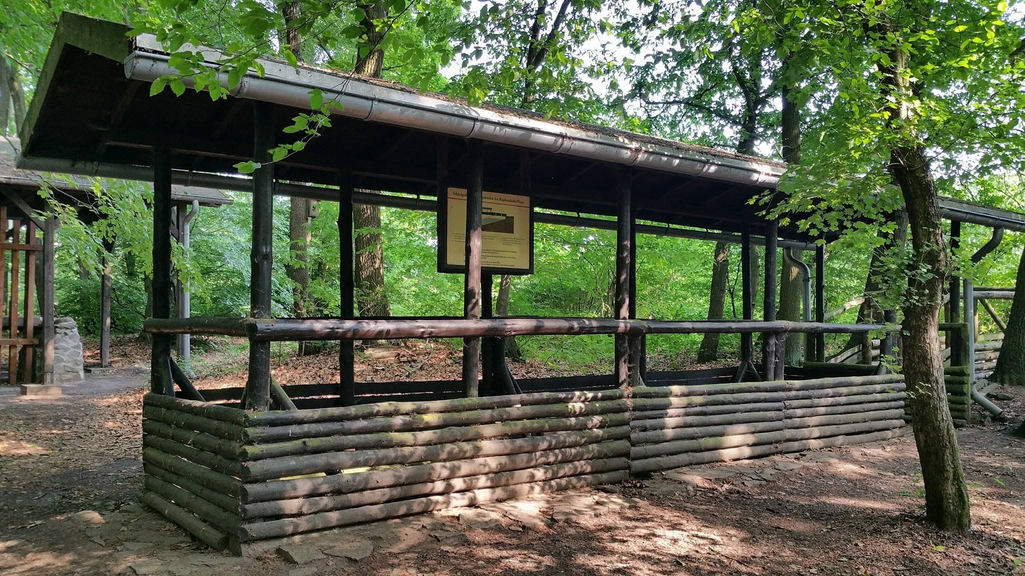 Plate-forme en bois couverte dans la forêt avec panneau d'information
