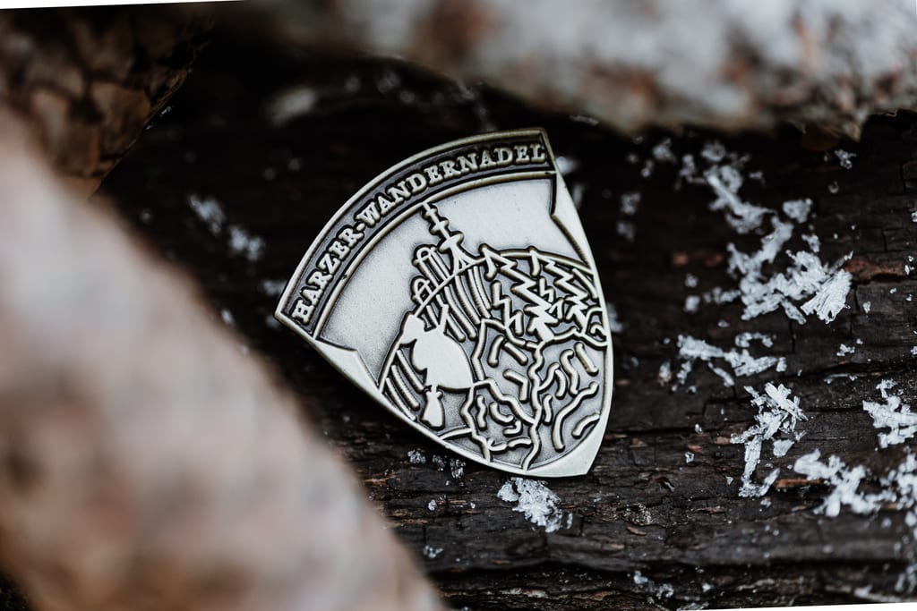 Insigne de l'aiguille de randonnée du Harz en bronze dans la forêt avec de la neige